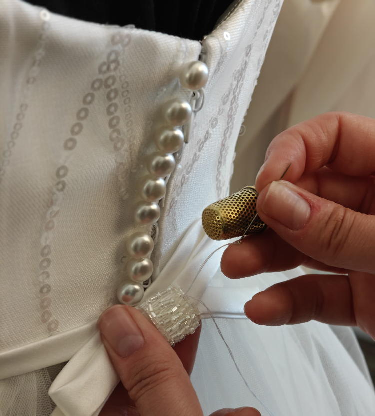 Chiusura con bottoni di perla e cintura ricamata Swarovski su abito da sposa elegante.