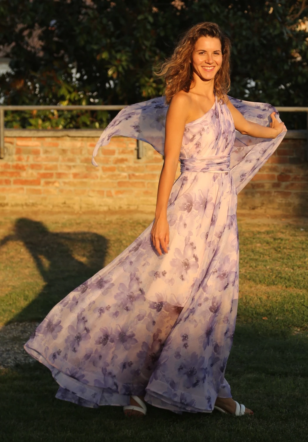 Abito monospalla viola a fiori con corpino drappeggiato in voile, cintura drappeggiata e ala.